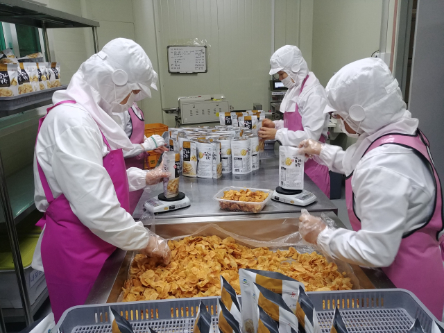 ▲ 추경희 대표(오른쪽 두 번째)와 근로자들이 위생복과 위생모, 마스크를 착용하고 방금 생산된 감자부각을 포장하고 있다.