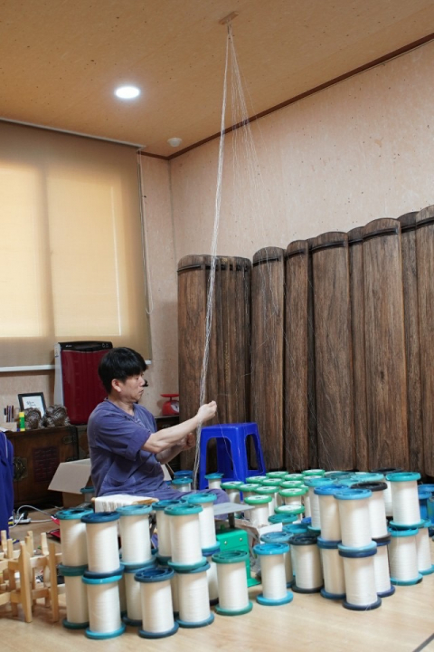 ▲ 가야금 명장 김동환씨가 전통방식으로 명주실을 꼬아 가야금 줄을 제작하고 있다.