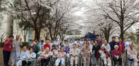 ▲ 입원 환자들이 벚꽃을 배경 삼아 단체 사진을 찍고 있다.