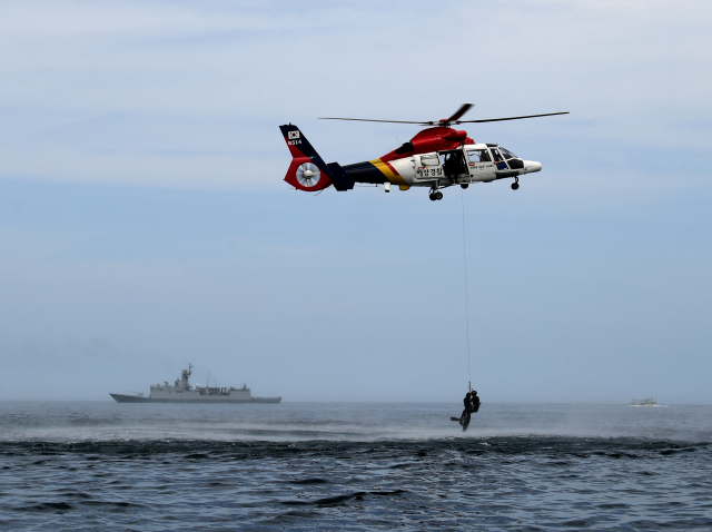 ▲ 해군 1함대가 동해지방해양경찰청과 함께 12일 강원도 동해 인근 해상에서 ‘합동 해상구조훈련’을 실시했다. 강원함(신형호위함, FFG)과 해경 헬기가 호이스트(구조용 승강장치)를 이용해 익수자를 구조하고 있다.
