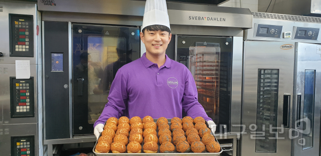 ▲ 투마루의 김용준(28) 대표가 갓 구워낸 ‘김천호두먹빵’을 들고 환하게 웃고 있다.