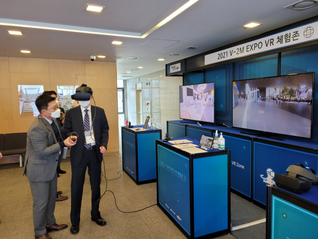 ▲ 오프라인 참가자가 VR 감상 장치를 이용해 가상 부스들을 둘러보고 있는 장면.