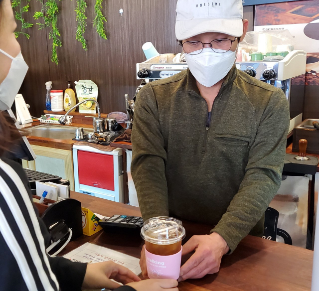 ▲ 영양에 한 카페 점원이 영양군보건소에서 제공한 컵 홀더를 활용해 손님에게 커피를 전달하고 있다.