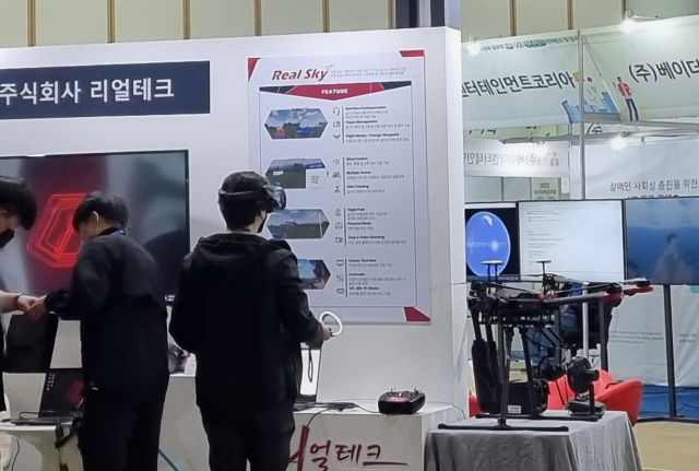 ▲ 12일 엑스코에서 개최된 ‘2021년 대구·경북 글로벌 AR·VR 메타버스 컨퍼런스 및 전시회’에 참가한 관람객이 리얼테크의 드론 비행교육 시스템을 체험하고 있다.