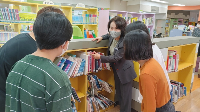 ▲ 정은향 대구동성초등학교장이 학생들과 함께 교내 도서관에 있는 책들에 대해 설명하고 있다.